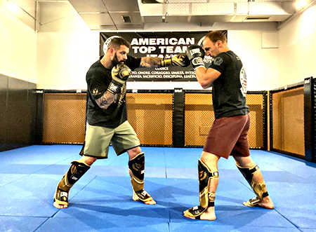Due uomini che praticano la boxe Thai-Kick in una palestra.