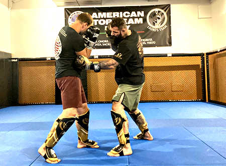 Due uomini impegnati in un Corso di Thai-Kick in una palestra.