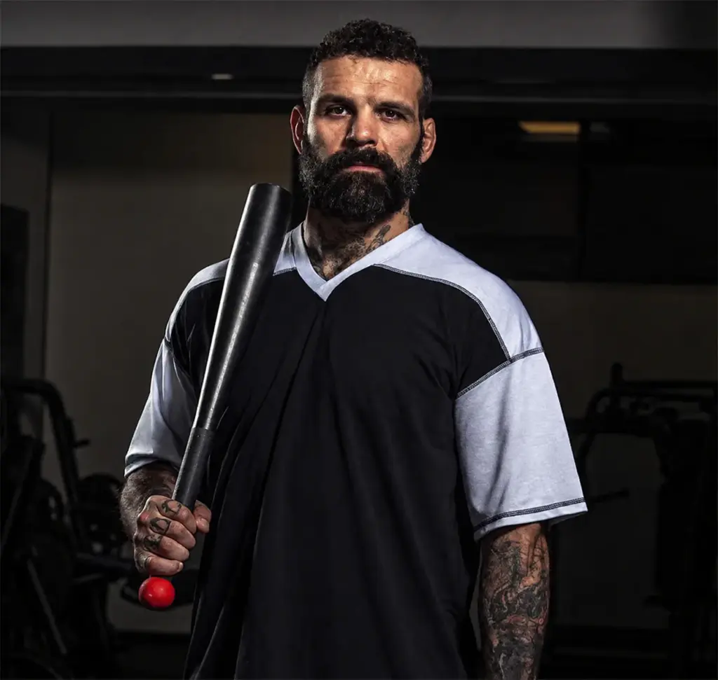 Uomo con mazza da baseball in palestra, pronto per l'allenamento.